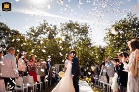 In Gorizia, Italy, the bride and groom share a celebratory kiss in bright sunlight on the aisle immediately after exiting, surrounded by a shower of confetti.